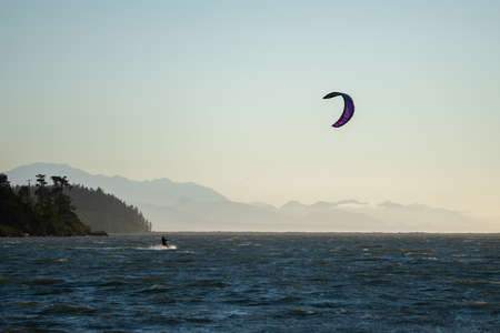 sunset kite surfing in the sea with mountains in the backgroundの写真素材