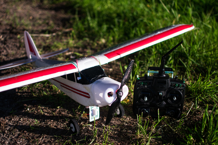 Red and white RC Plane out of styropor in nature with green grass in top down with black transmitter for radio control.の写真素材