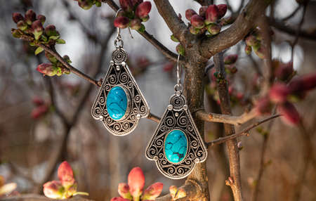 Vintage shiny earrings isolated on tree branches with blur background. Luxury fashion product for commercialの写真素材