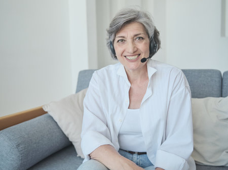 Senior woman communicating on a video call with friends, recording an educational videoの写真素材