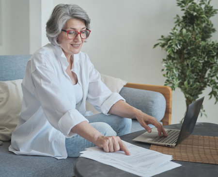 Focused senior woman using computer for research and creative workの写真素材