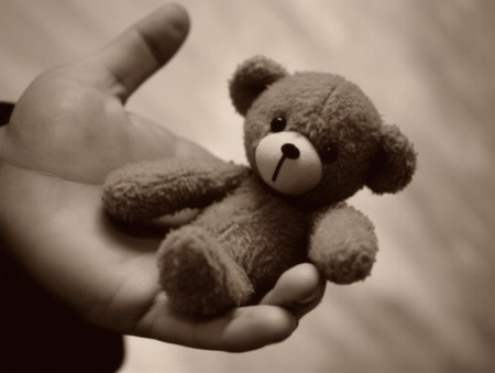 A disabled persons hand holding a raggedy teddy bear symbolizing hope in the face of poverty.. AI generationの素材