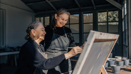 Two senior women painting together in art studioの素材