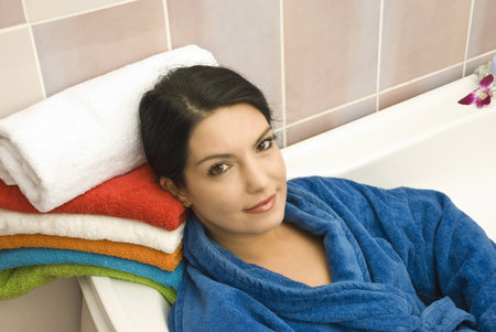 Woman relaxing in bathtub wearing a bathrob