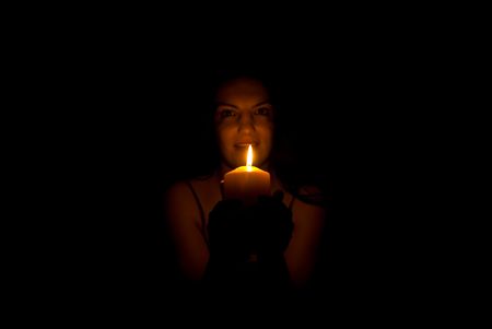 Smiling woman holding a candle light in darknessの写真素材