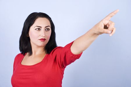 Beautiful woman in red pointing to copy space and looking awayの写真素材