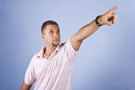 Mid adult man with pointing hand to copy space and looking up on blue backgroundの写真素材