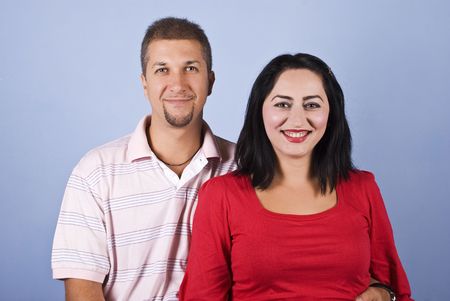 Happy mid adult couple standing together and laughing on blue backgroundの写真素材