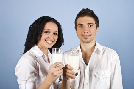 Youth happy couple holding glasses with milk and smiling,they wear white clothes on blue backgroundの写真素材