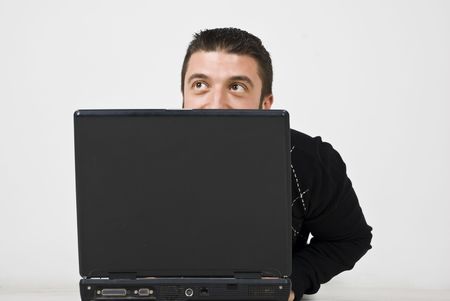 Man  lying down on wooden floor and looking up  behind a laptop and smiling ,he spying  or just have fun hidingの写真素材