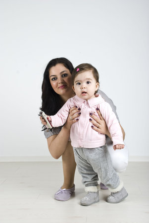 Mother holding her lovely baby girl  and smiling for you