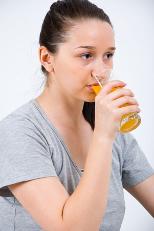 Young woman drinking orange juice  in profile looking away