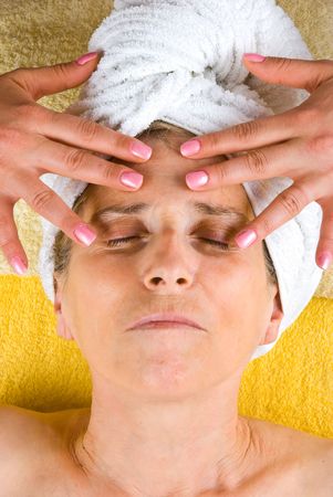 Senior woman lying with eyes closed and receiving a facial massage  at spa resortの写真素材