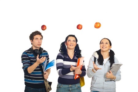 Three cheerful students throw up apples and having fun isolated on white backgroundの写真素材