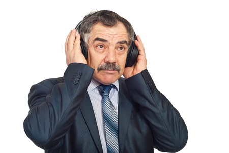 Mature corporate man listening music in headphones and looking up isolated on white backgroundの写真素材