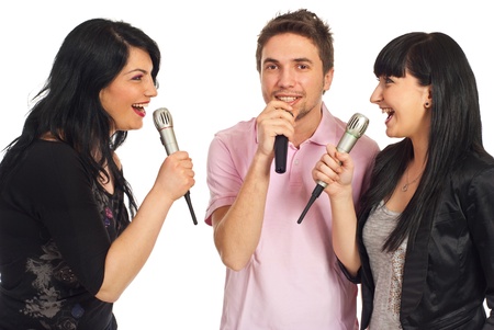 Happy three friends singing in microphones at karaoke party and having fun isolated on white backgroundの写真素材