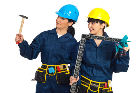 Two workers women holding construction tools and looking away   isolated on white background