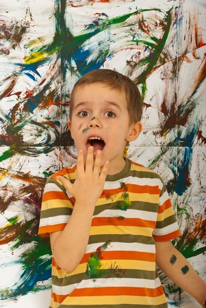 Surprised messy boy  after painting with hands a wall の写真素材