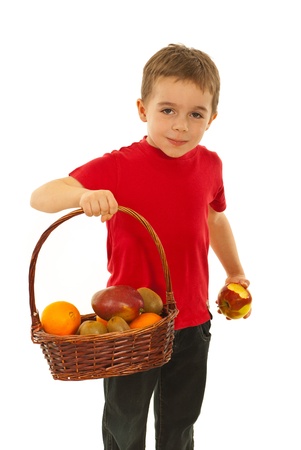 Hungry boy eating apple and holding up full basket of fruits isolated on white backgroundの写真素材