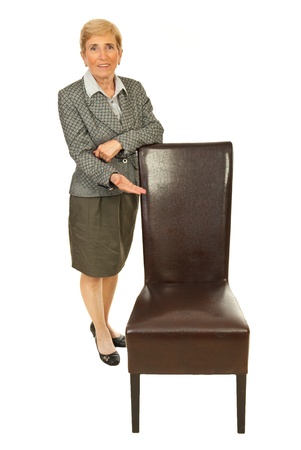 Senior executive woman invite you to sit on empty chair isolated on white backgroundの写真素材