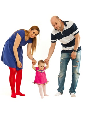 Full length of parents helping baby to make first steps isolated on white backgroundの写真素材