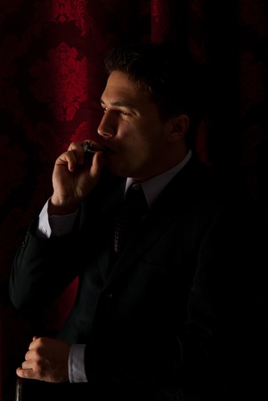 Profile of elegant man smoking in night and looking to the lightの写真素材