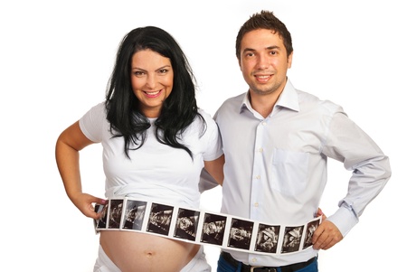 Couple holding long  number of ultrasound images in front of their bellys isolated on white backgroundの写真素材