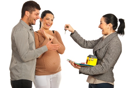 Happy real estate agent woman giving keys to pregnant couple isolated on white backgroundの写真素材
