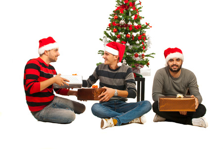 Three friends men celebrate Christmas and sitting on floor near treeの写真素材