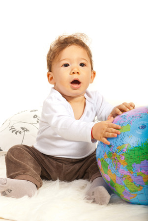 Amazed baby with world globe sitting on fur blanketの写真素材