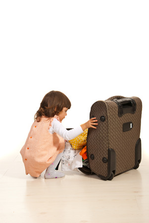 Little girl prepare for trip and putting clothes in luggageの写真素材