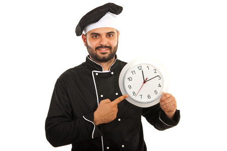 Chef male in black uniform pointing to big clock isolated on white backgroundの写真素材