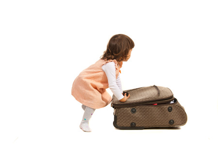 Toddler girl pushing luggage isolated on white bakgroundの写真素材