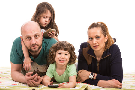 Cheerful family with two kids laying on blanket against white background