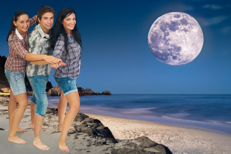 A woman standing on a beach at night, smiling under the full moon.の写真素材
