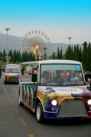 CHIANGMAI, THAILAND - MARCH 13 2012: Shuttle bus service in area of Royal Flora Ratchapruek Park with colorful ferris wheel background.のeditorial素材