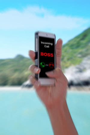 "Incoming call BOSS" showing on the smartphone with tropical island background. (zoom effect)の写真素材