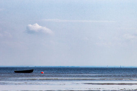 lonely boat moored near the shore against a backdrop of sailboats
