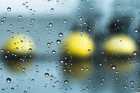 drops of rain on glass on background of yellow spheres balls