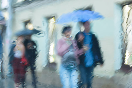 It 's raining hard, through the window. Blurred silhouettes of people in the city go about their...