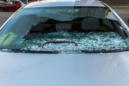Broken rear glass of car, spread fragments of glass on asphalt