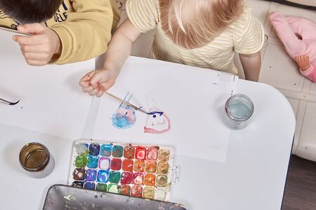 Children brother and sister paint together water paints view from above.の写真素材