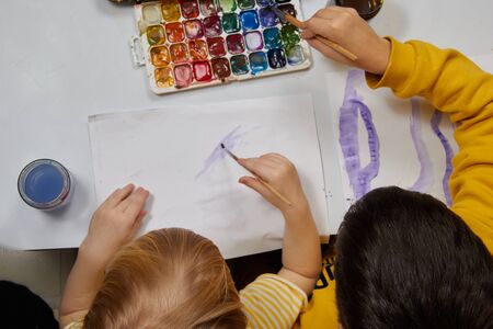 Children brother and sister paint together water paints view from above.の写真素材