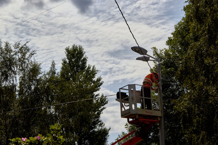Saint Petersburg, RUSSIA - July 11, 2019: workers in lift bucket repair street light pole with...