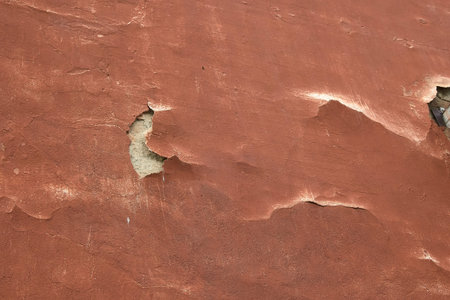 the old plaster on the orange wall is falling off in a big chunk.