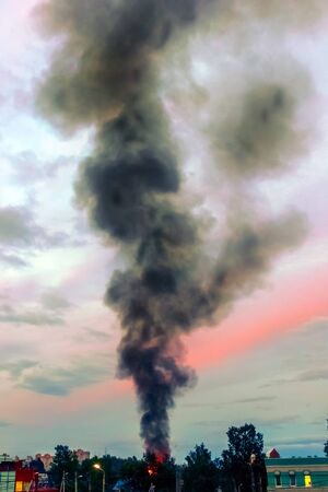 the building burns with fire and black smoke against the evening sky.の写真素材