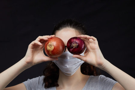 Young woman in protective mask holding onion . Preventive measures against disease.