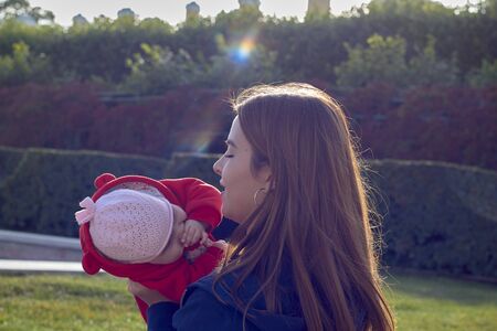 a young mother with a child at the green fence in the summer in the Park close upの写真素材
