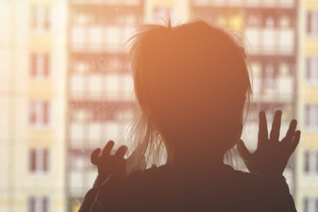 Dark silhouette of a child in the background of an apartment buildingの写真素材