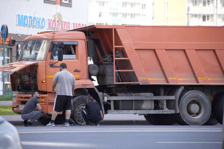 Russia, Saint-Petersburg, July 2019: the truck has a punctured wheel the driver is trying to repair it on his own.のeditorial素材